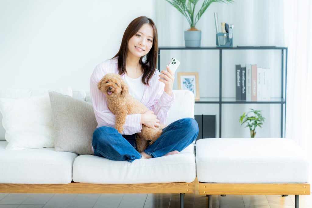 犬を抱えてスマホを触る女性