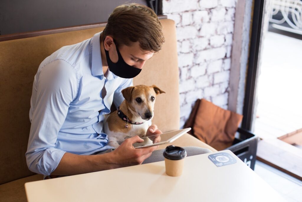 カフェで犬とタブレットを見る男性