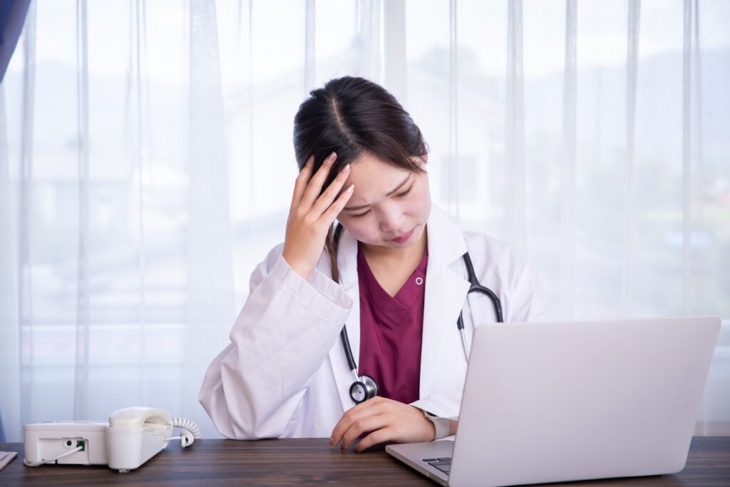 パソコンの前で頭をかかえる女性医師