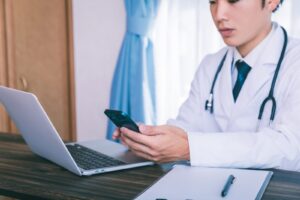 PCとスマホを見る医師