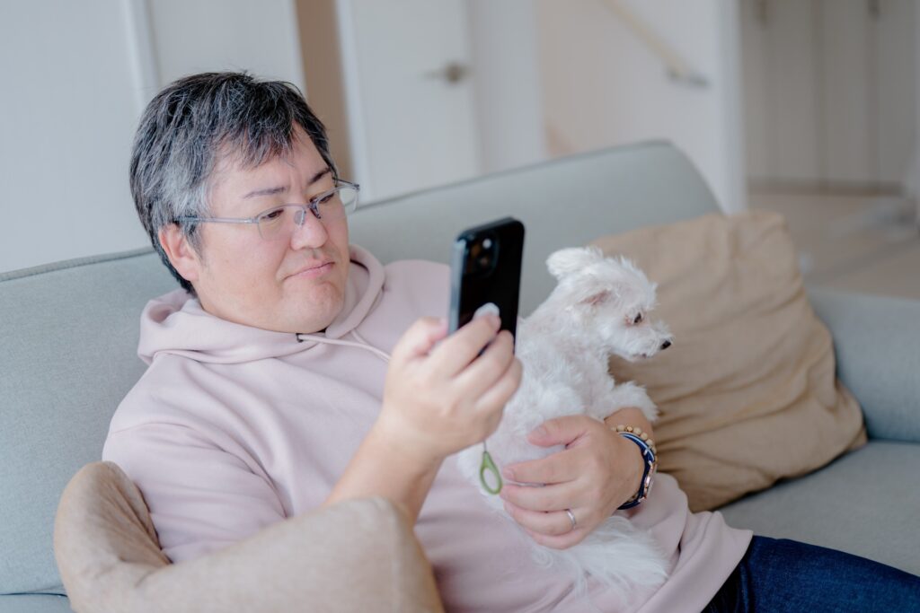犬を抱えながらスマホを見る男性