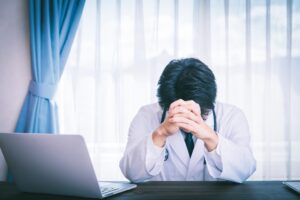 パソコンの前で悩む白衣の男性