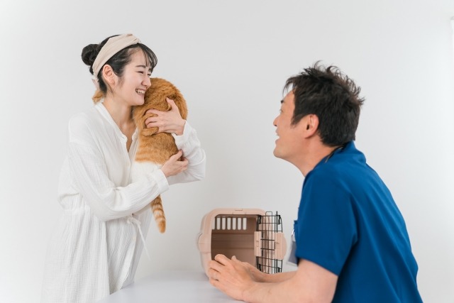 猫を抱き上げる飼い主と獣医師